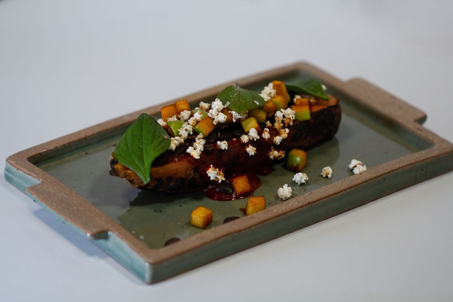 Shredded braised Elk with purple mush in a sage green ceramic bowl on a white surface.