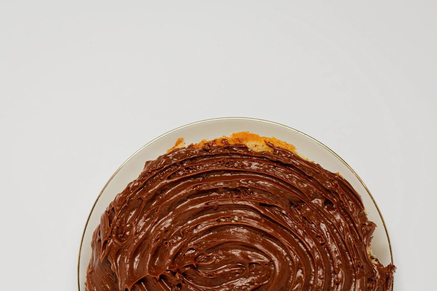 Beautiful chocolate frosting spread in a circular motion on yellow cake on a white surface. Food and beverage photography, B. Steele Images.