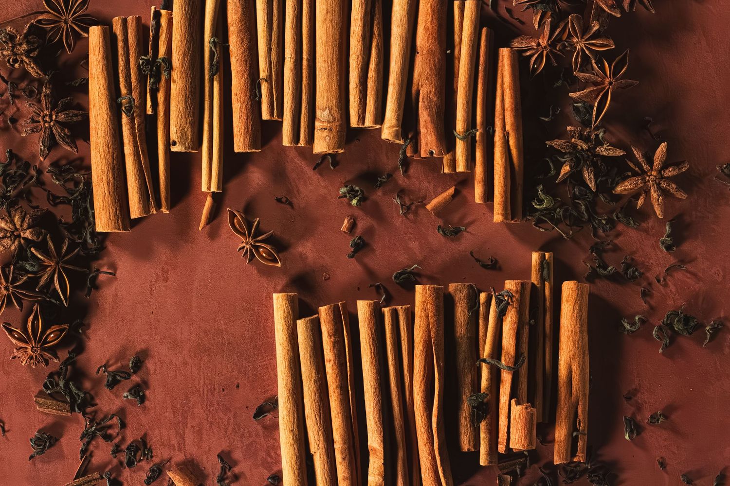 Cinnamon sticks and star anise spices arranged on a rich brown surface. B. Steele Images, food & beverage photography.