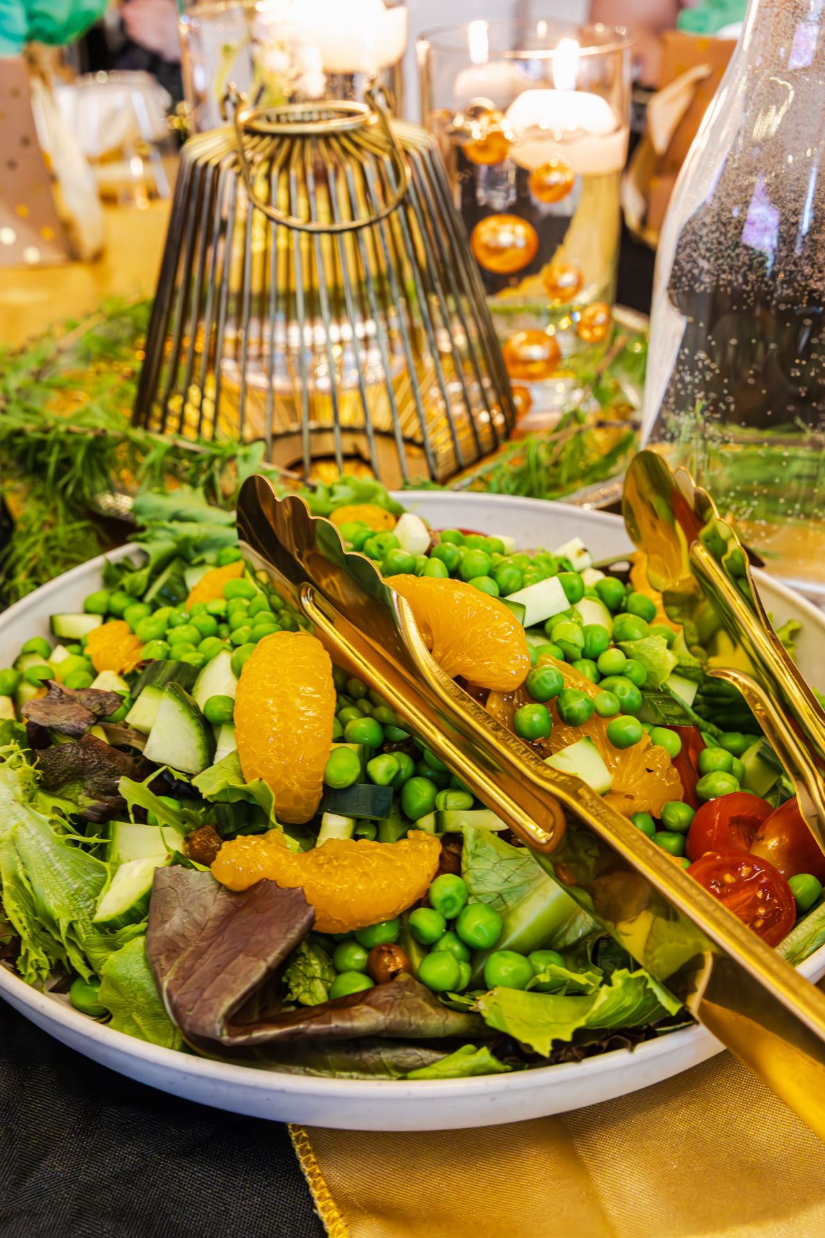 Fresh garden salad with green peas, mandarin oranges, cherry tomatoes, and mixed greens served with gold tongs. B. Steele Images. Food photo