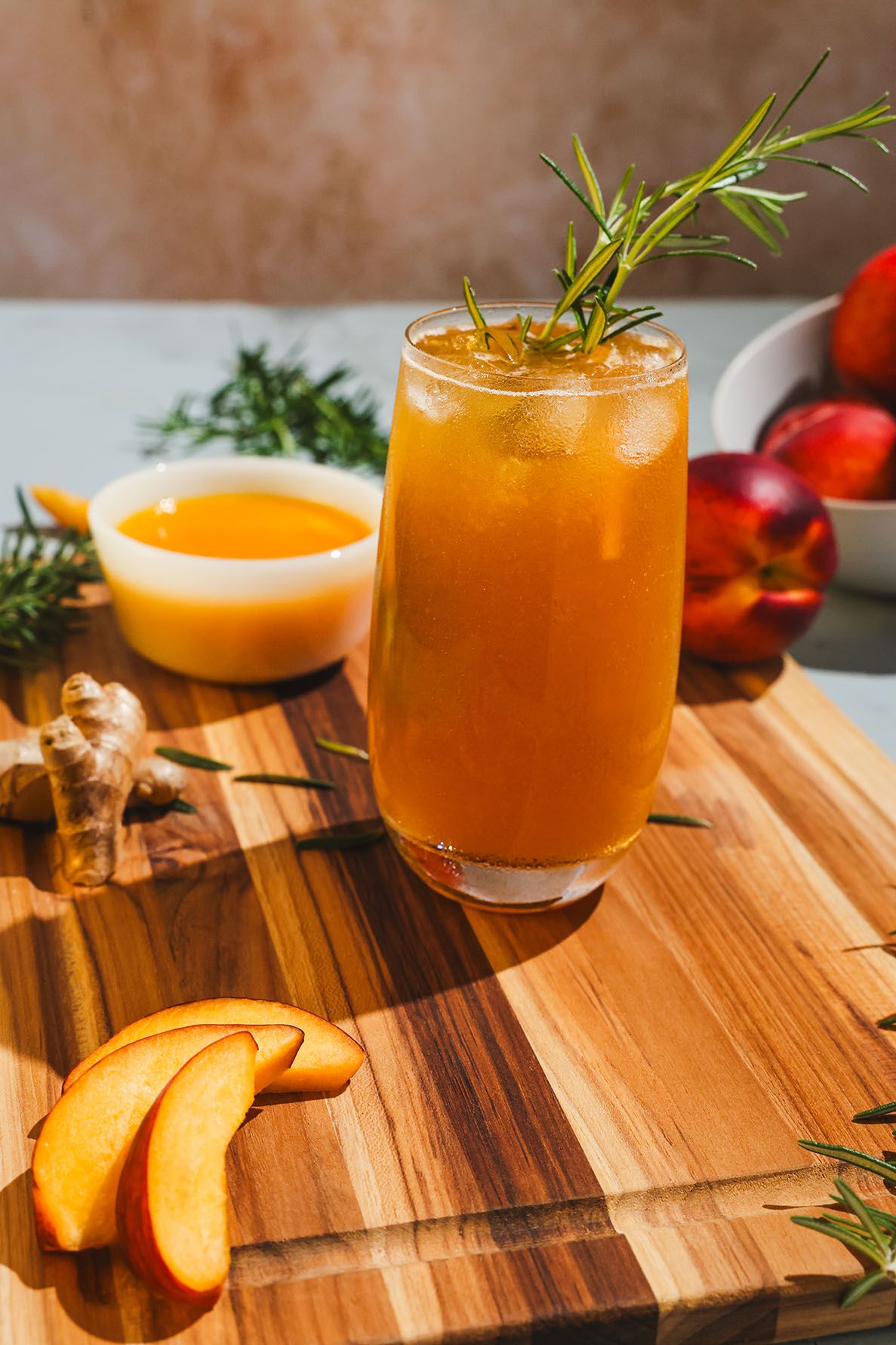 Orange Bundaberg mocktail garnished with fresh rosemary sprig served in a coupe glass on wooden surface. B. Steele Images, food photography