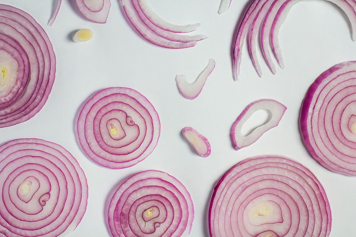 Thinly sliced red onions arranged in a various pattern against a white background. B. Steele Images, styling photography