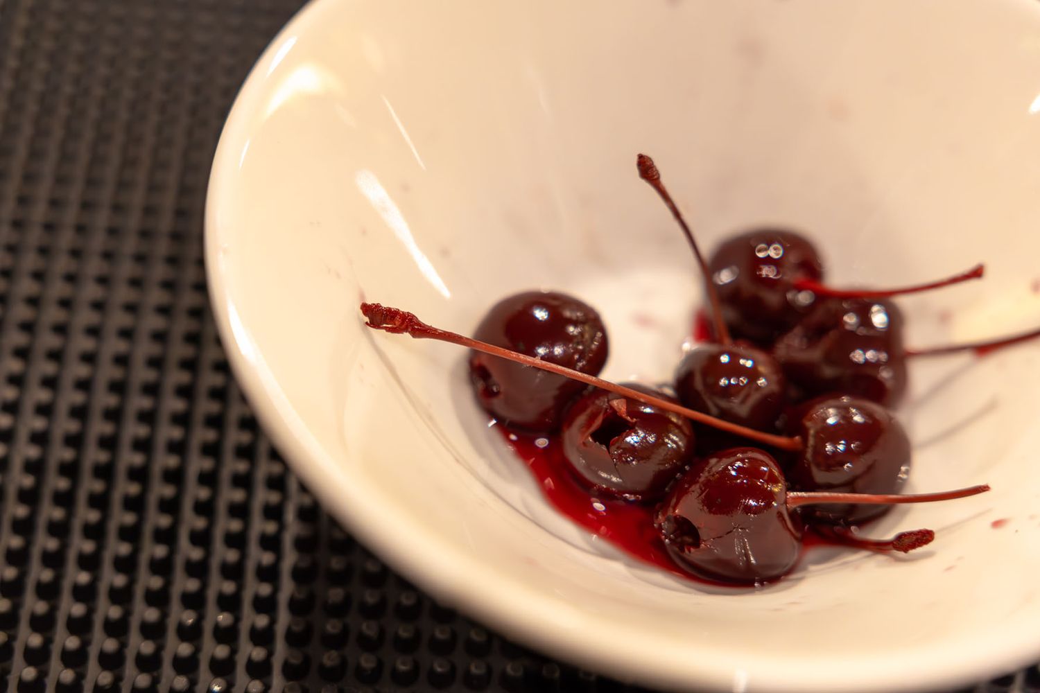 Cherries in a small white dish, on the bar. B. Steele Images, food and beverage photography