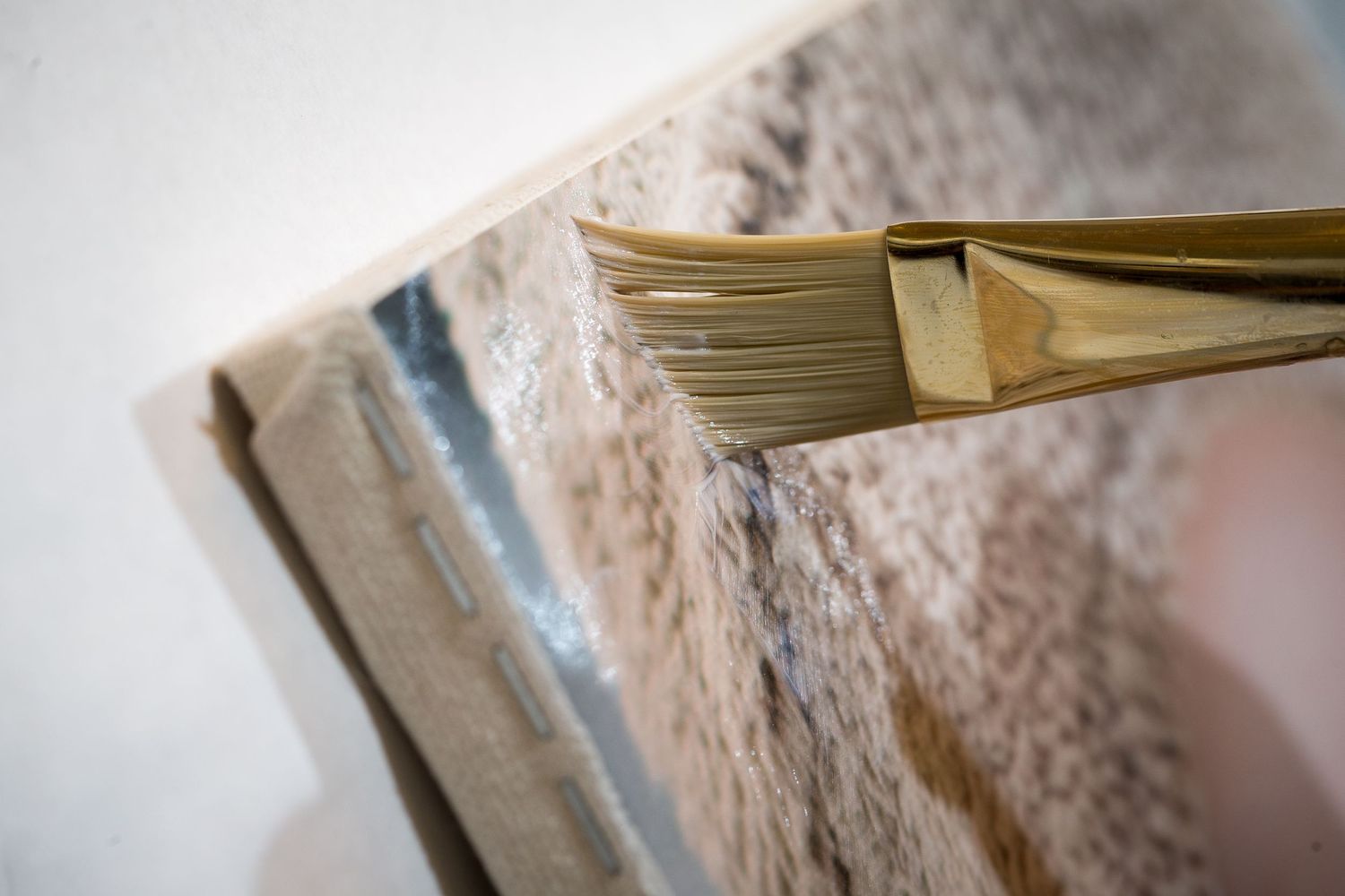 Close-up macro shot of a paintbrush applying paint to a canvas surface.