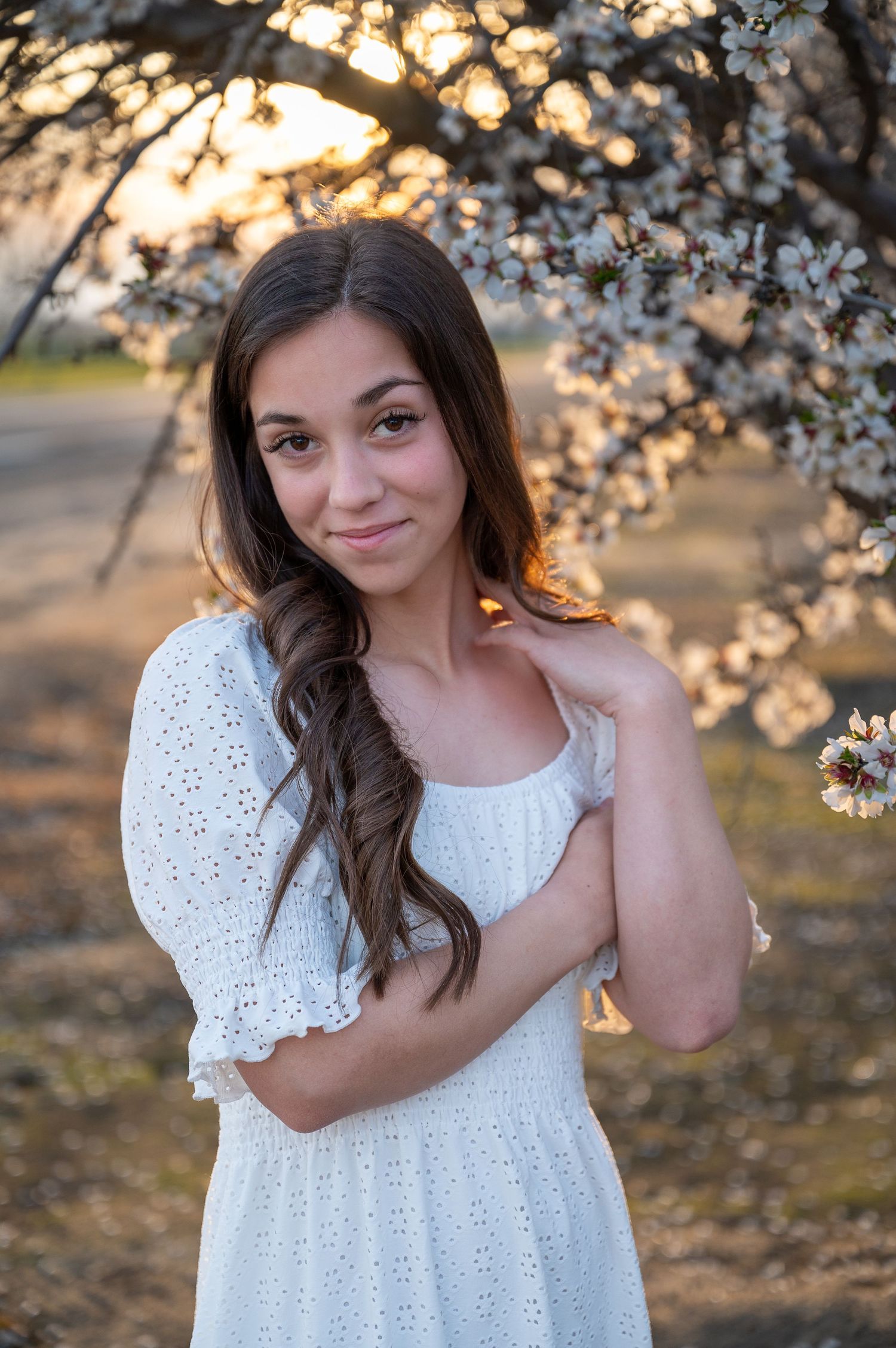 Golden sunset light illuminates spring blossoms as a white dress creates a dreamy orchard scene.