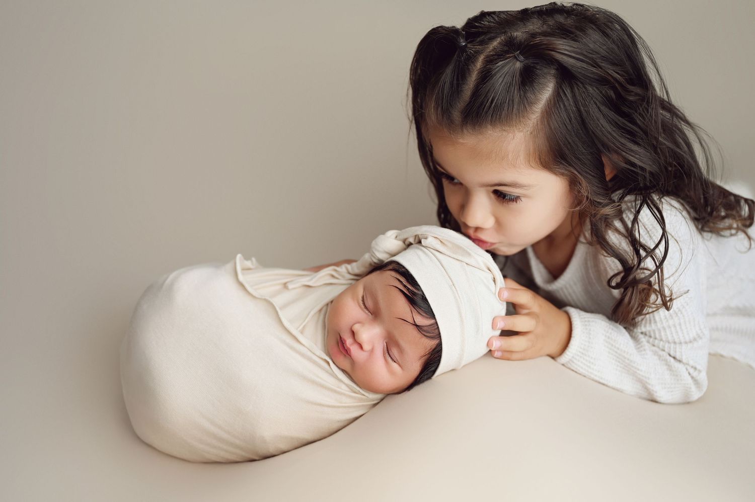 Artistic newborn photography series with baby wrapped in white against neutral background. Hanford Newborn Photographer