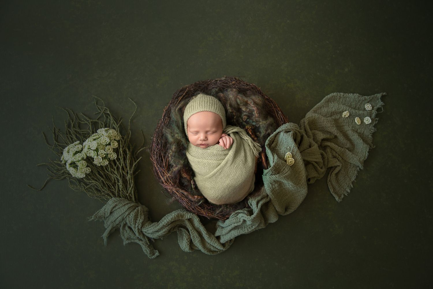 Newborn photography with vintage-style props and dark moody lighting.