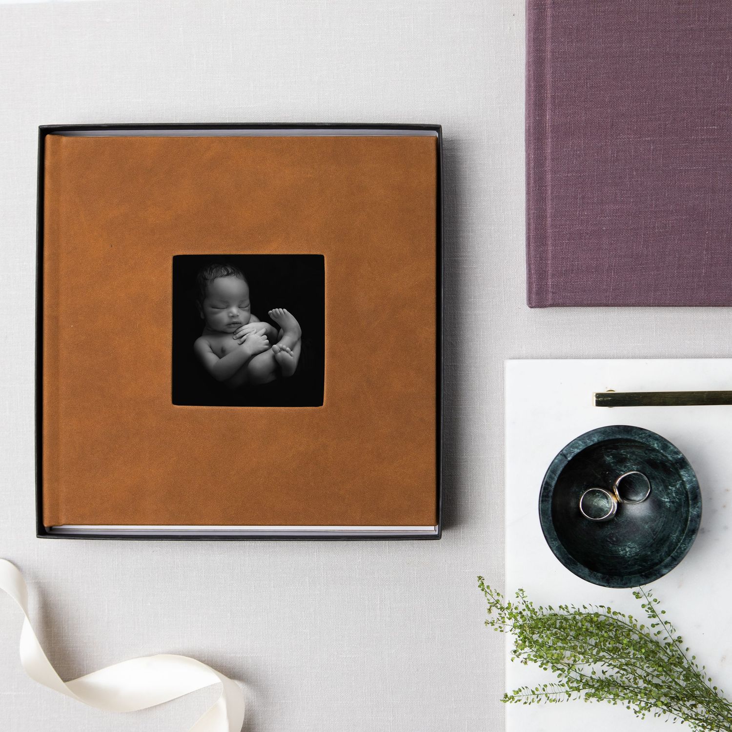 Brown leather photo album with a small black and white baby photo in the center.