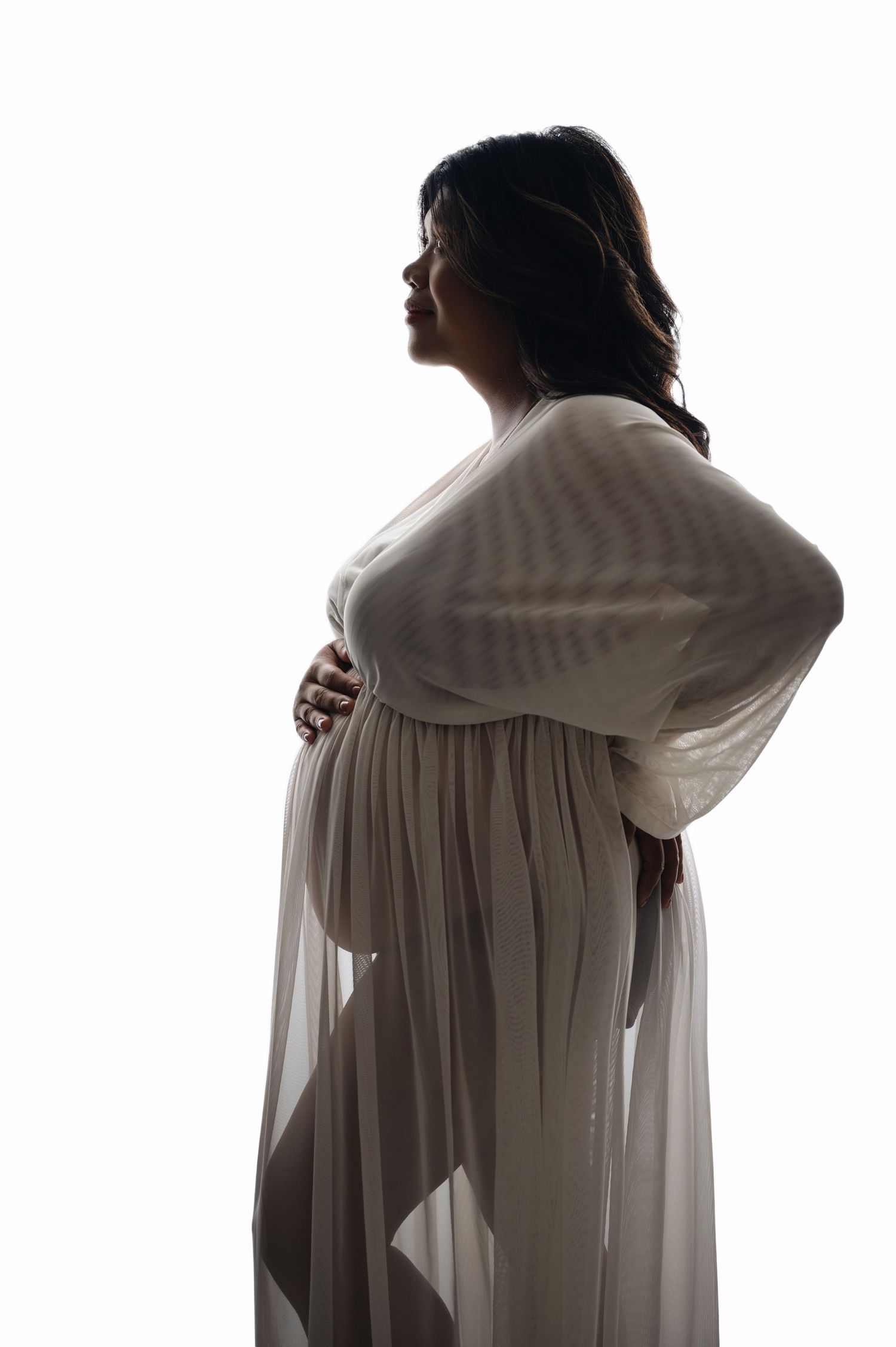 Ethereal maternity silhouette with flowing fabric against bright background. Hanford Maternity Photographer
