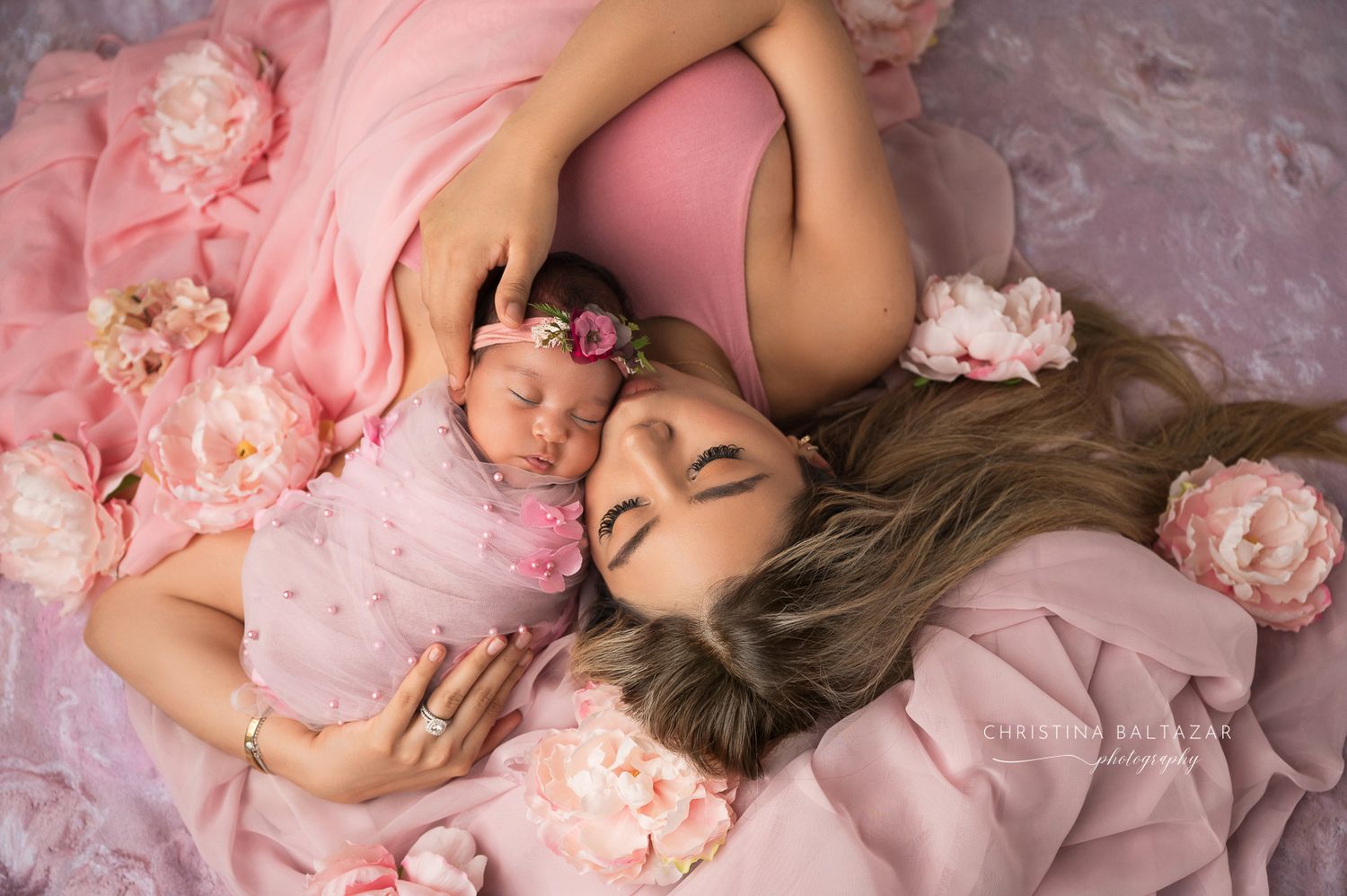 Overhead portrait featuring pink flower petals and soft tulle fabric creating a dreamy ethereal scene. Fresno Newborn Photographer