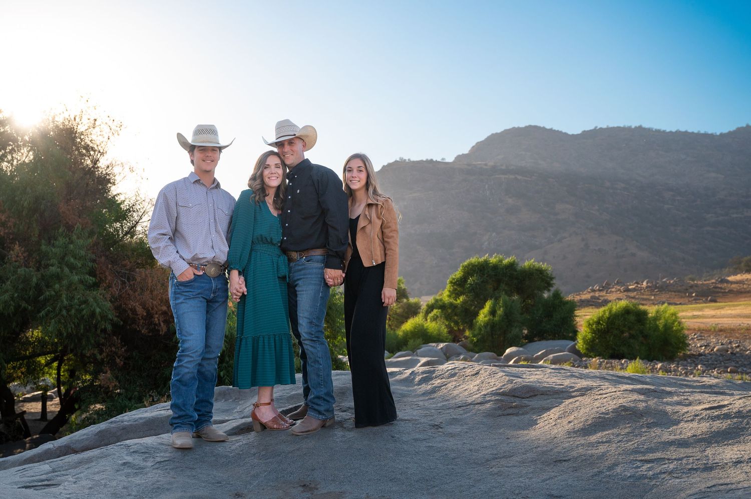 Group enjoying sunset views from a rocky overlook with mountains in the background. Fresno Family Photography
