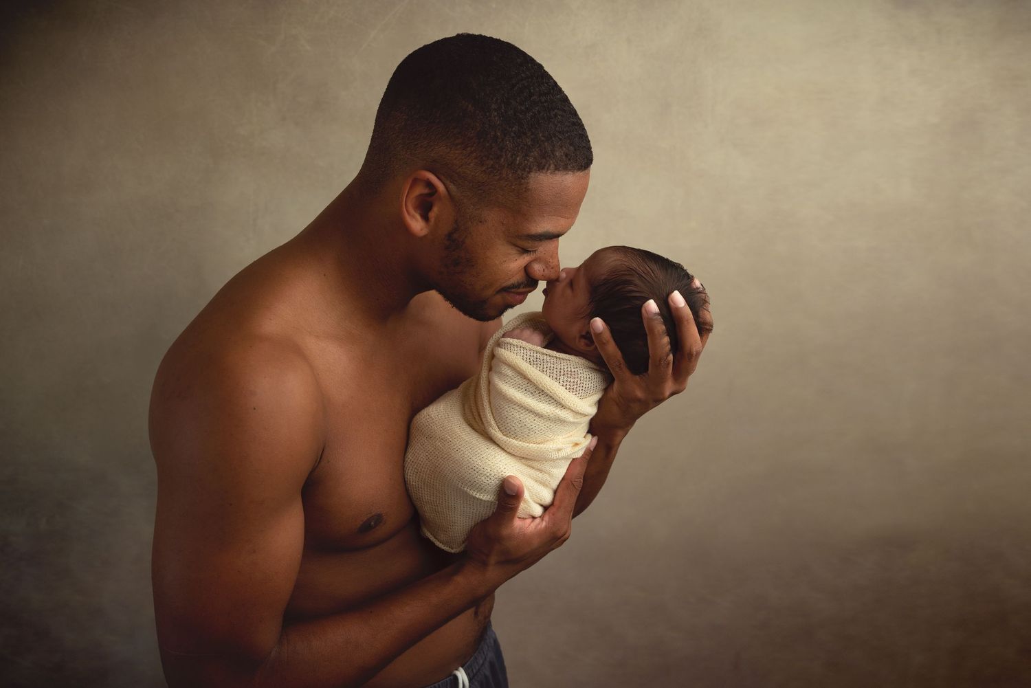 Artistic newborn photography session with dramatic lighting and neutral tones.