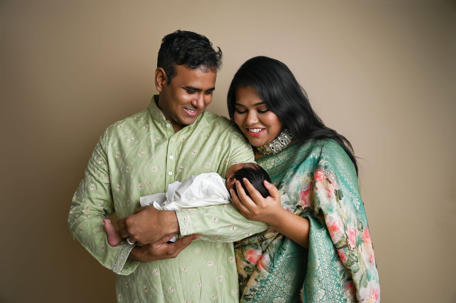 Sweet family newborn photography session in soft green and floral outfits.