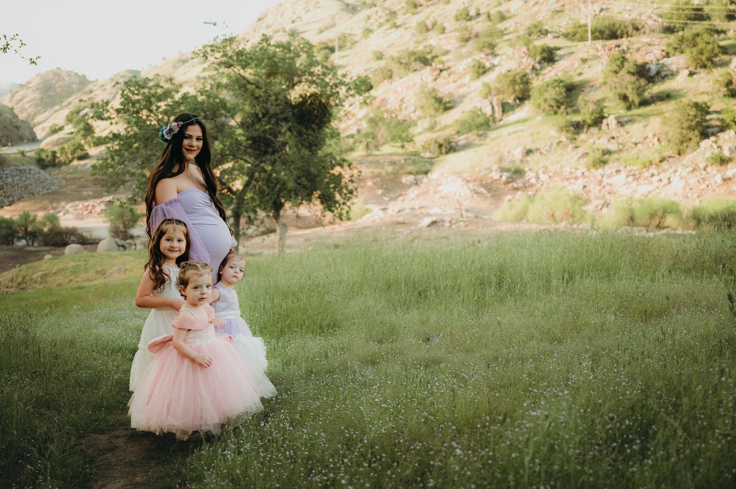 Two figures stand in an open grassy field with rolling hills in the background. Fresno Family Photography