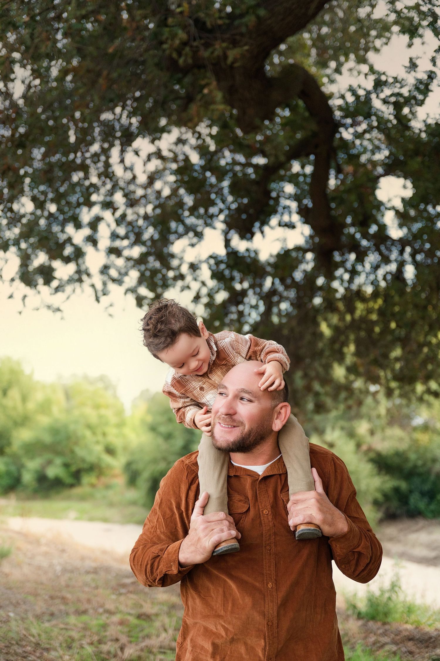 Fun candid moments captured under oak tree branches during a casual outdoor portrait session. Hanford Family Photographer