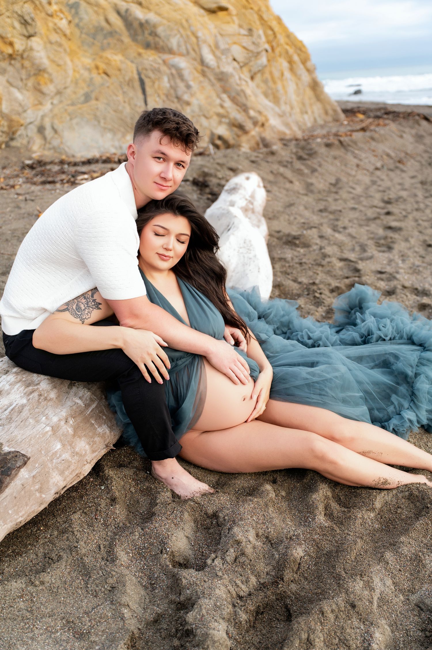Intimate maternity portrait on beach with teal flowing dress.