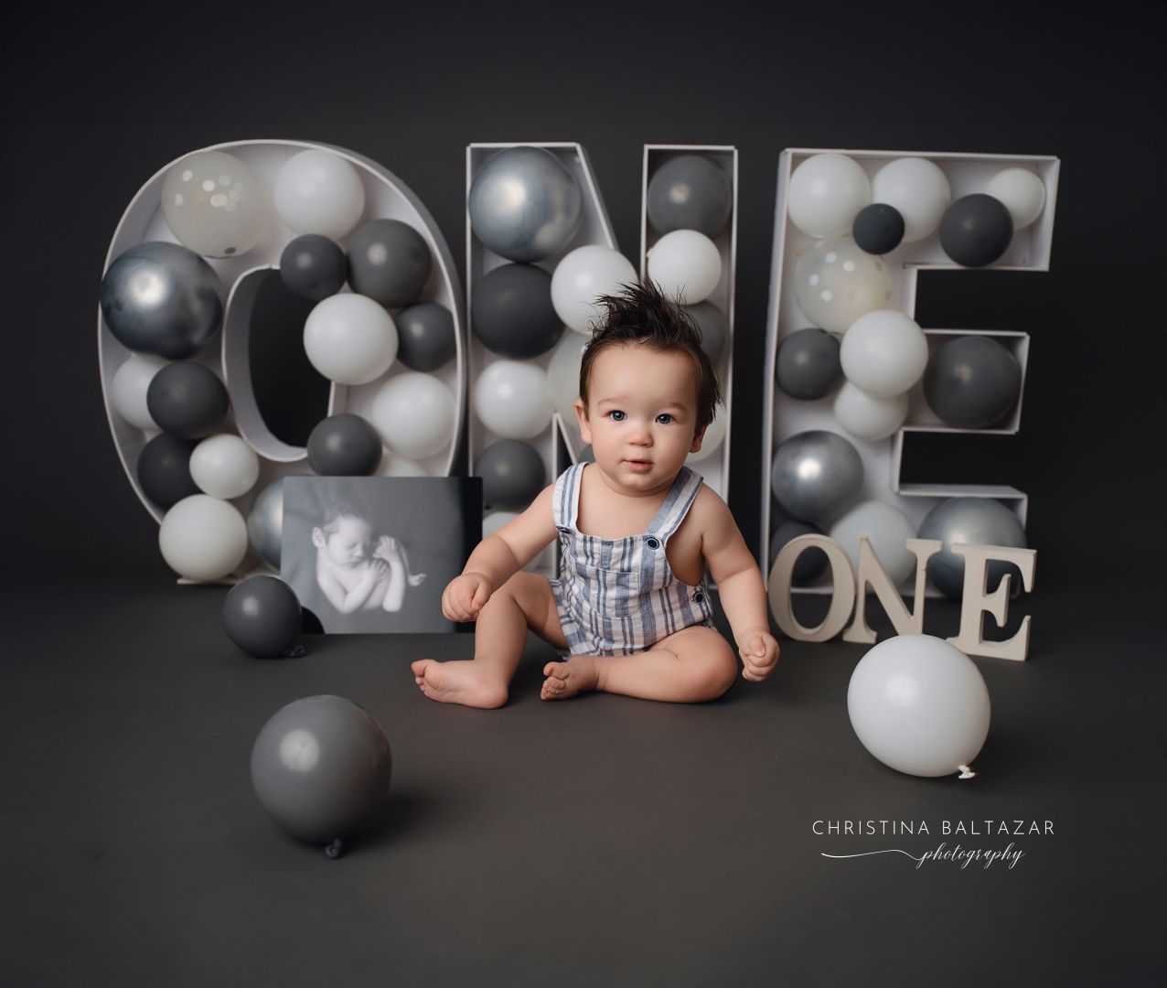 First birthday photo with ONE letter decorations and black and white balloons. Fresno Baby Photographer