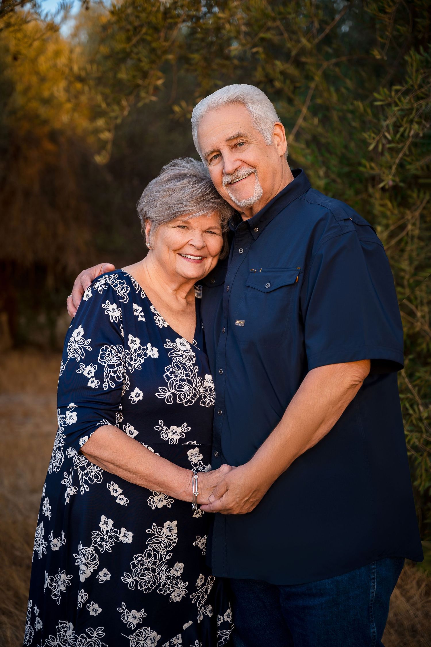 Loving couple in navy and floral outfits sharing tender moments outdoors. Hanford Family Photographer