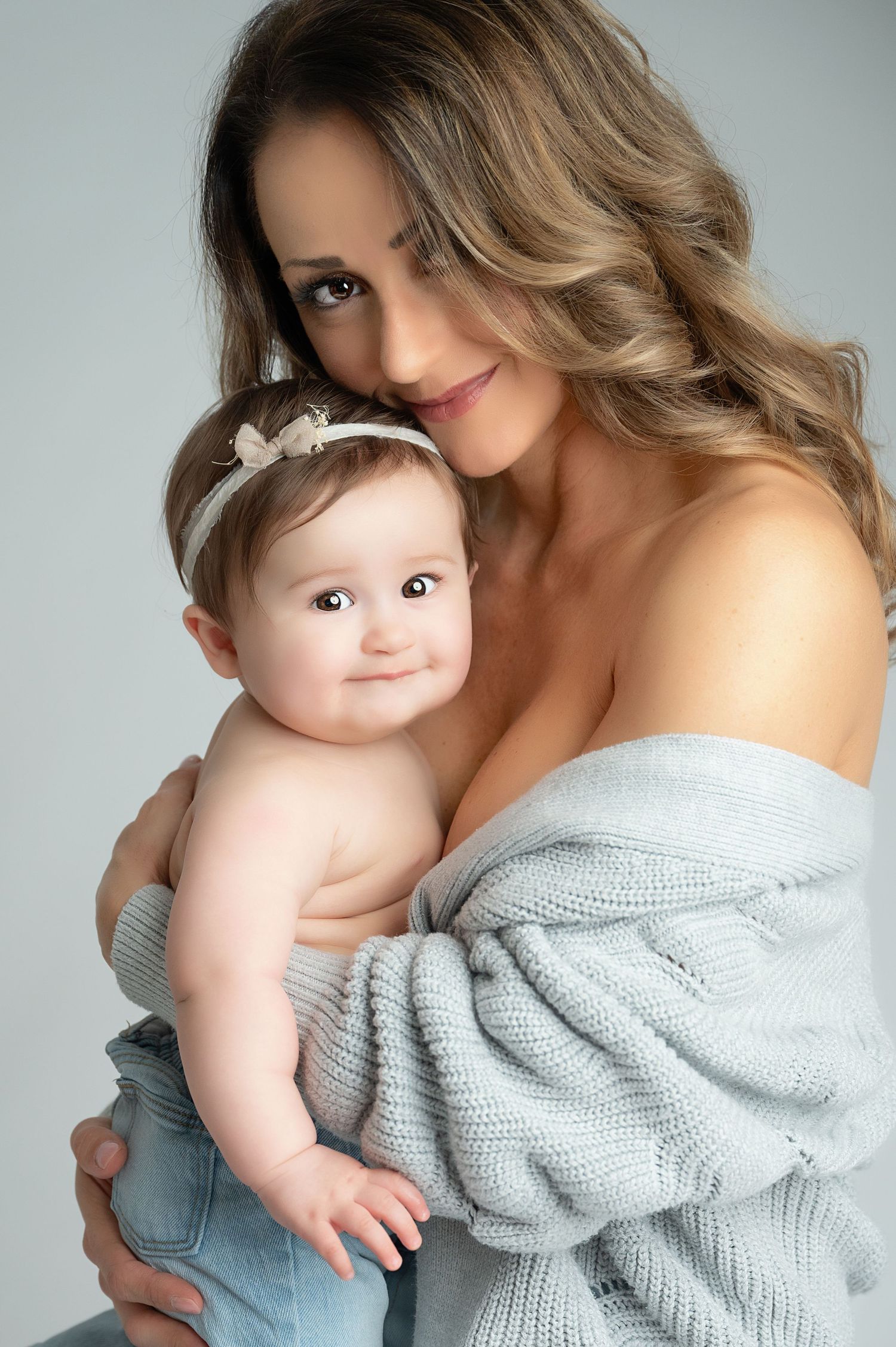 Intimate mother-child portrait with soft gray sweater and matching outfits.