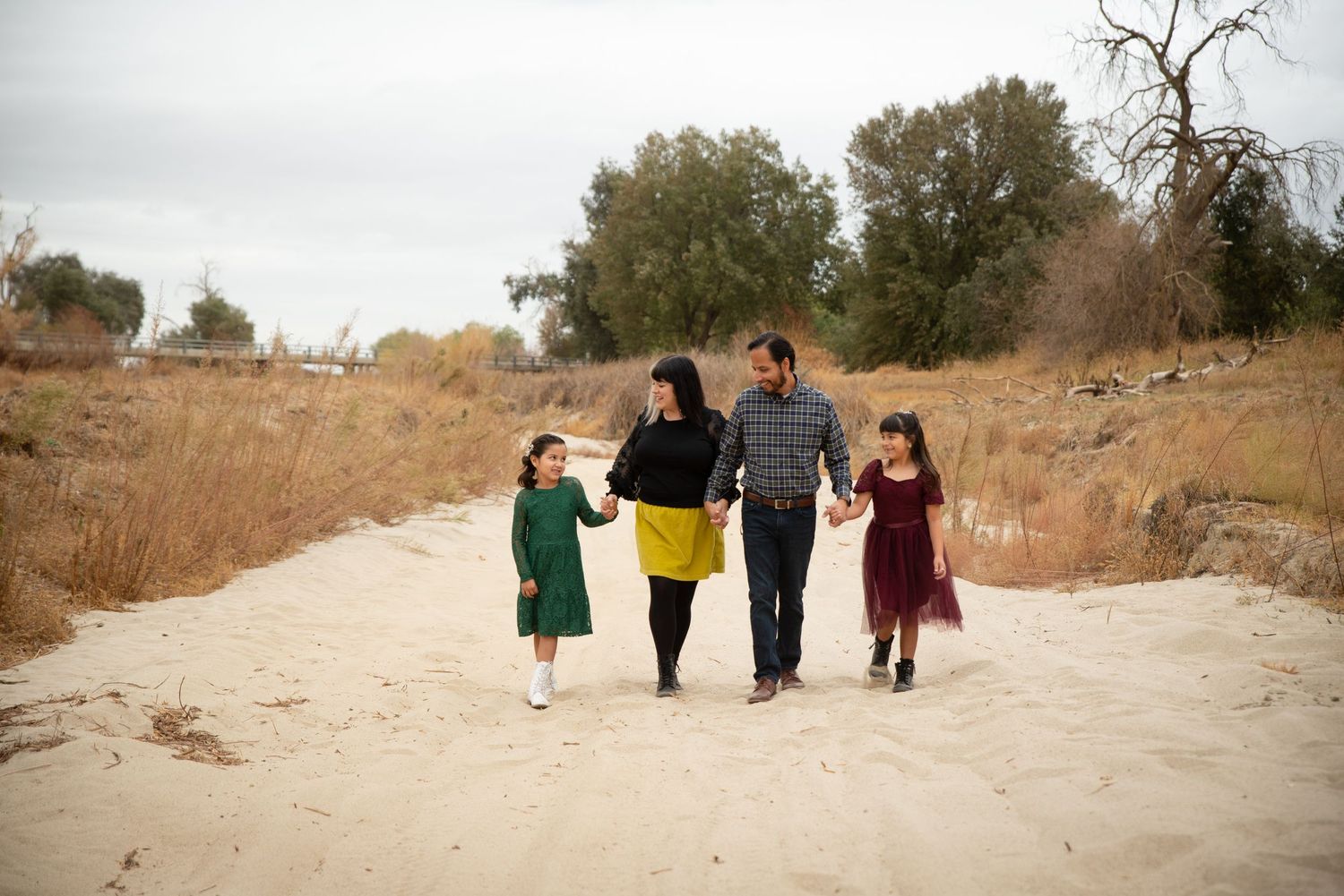 Family of 4 walking holding hands in dry riverbed Fresno Family Photography