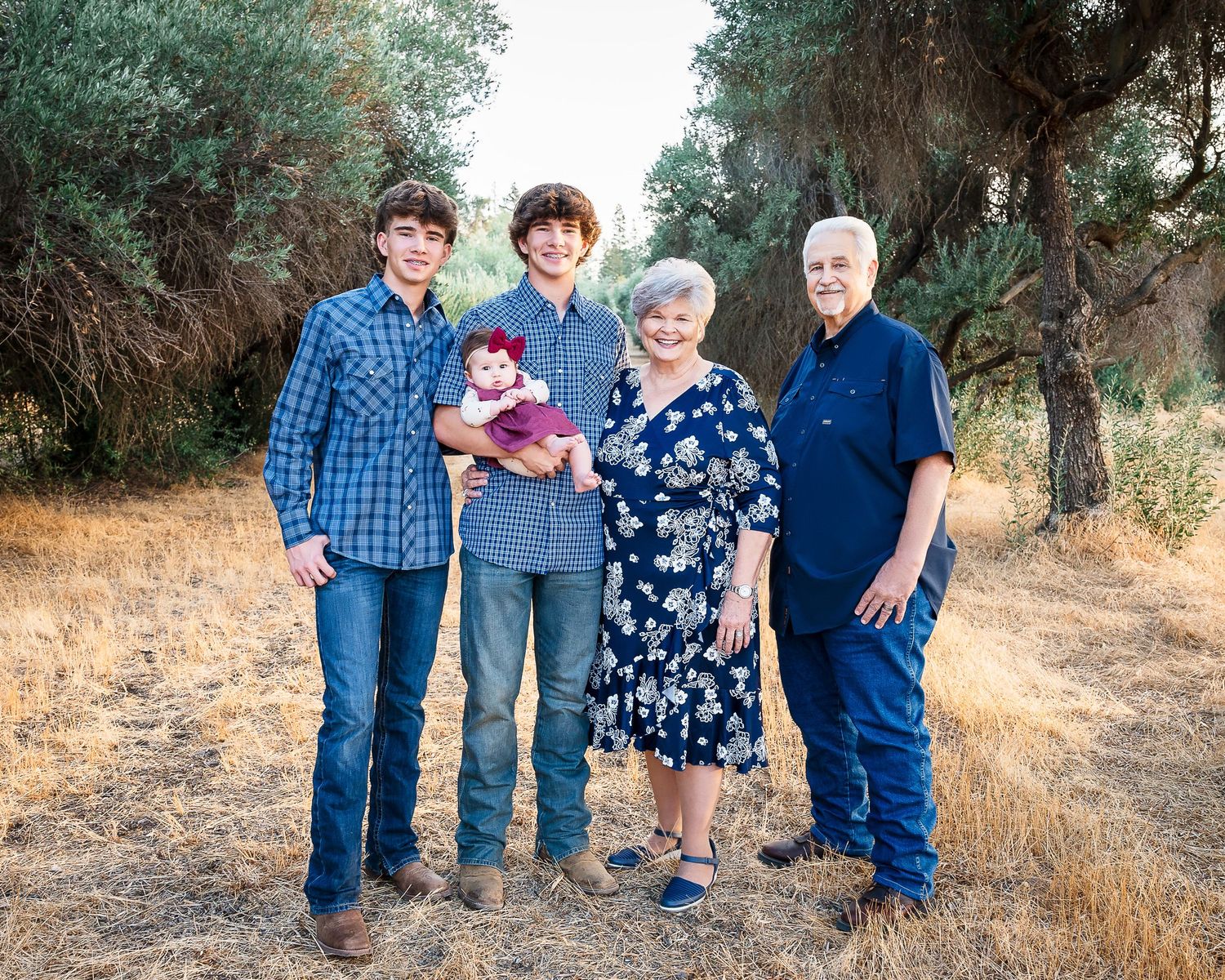 Multi-generational family gathering outdoors in casual attire against a natural backdrop. Hanford Family Photographer