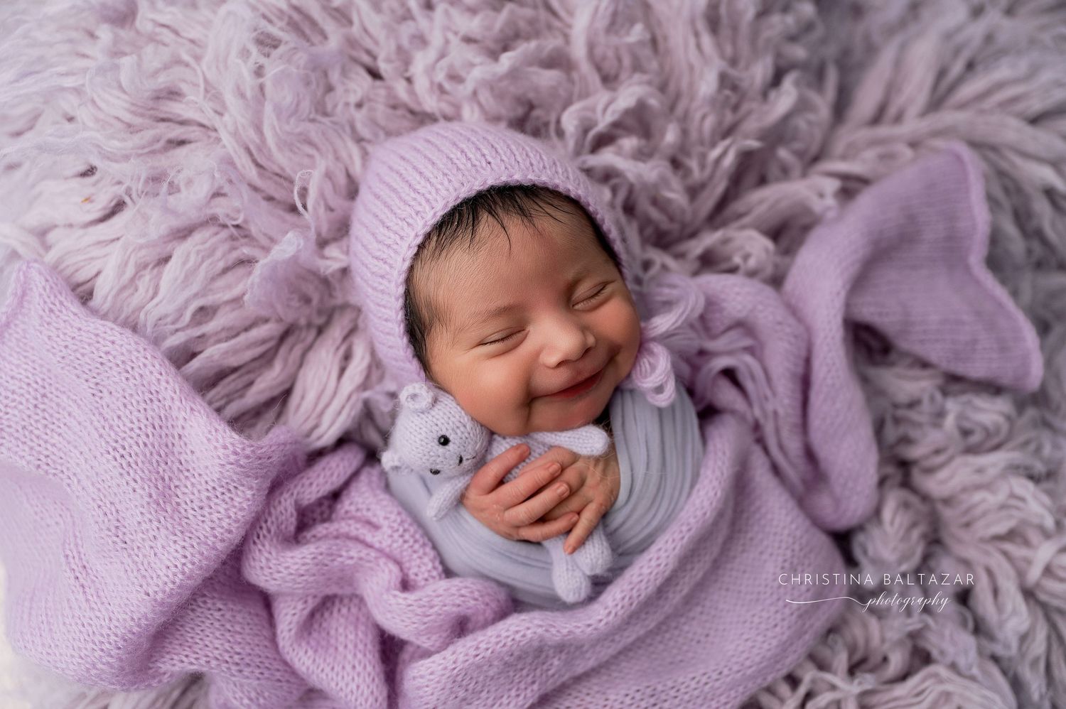Newborn baby sleeping peacefully on soft purple blankets in a professional photography session. Fresno Newborn Photography