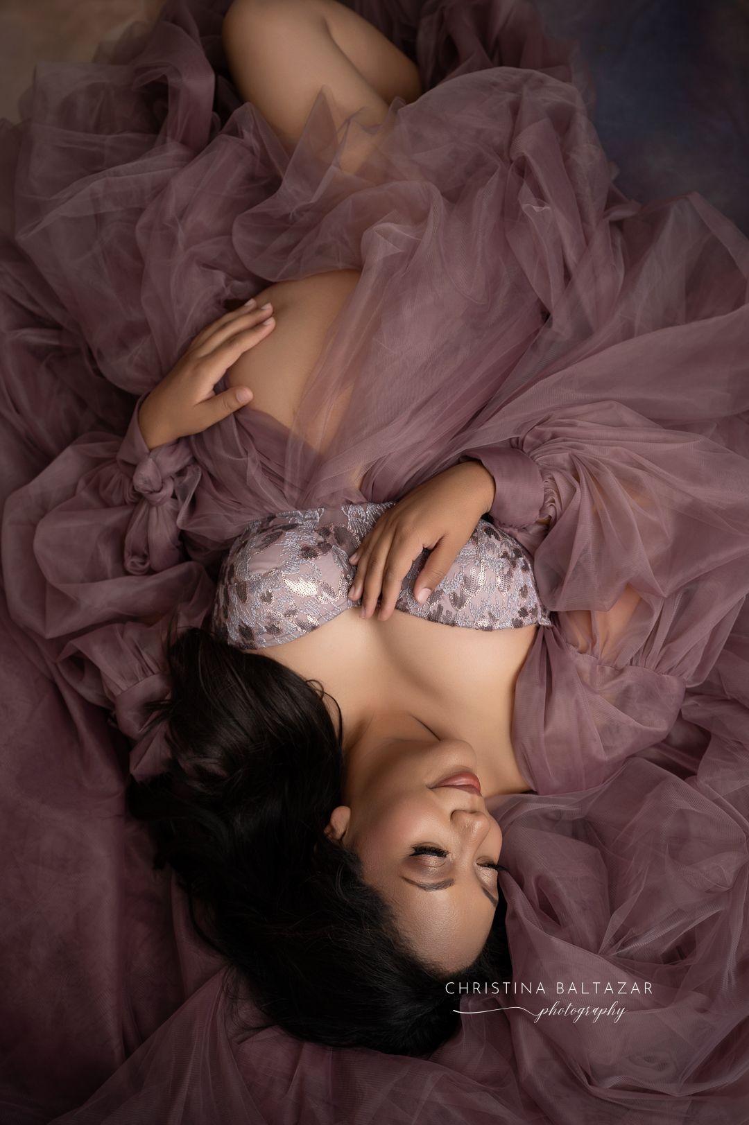 Dreamy boudoir portrait with flowing mauve tulle fabric and embellished lingerie in moody lighting. Fresno Maternity Photographer