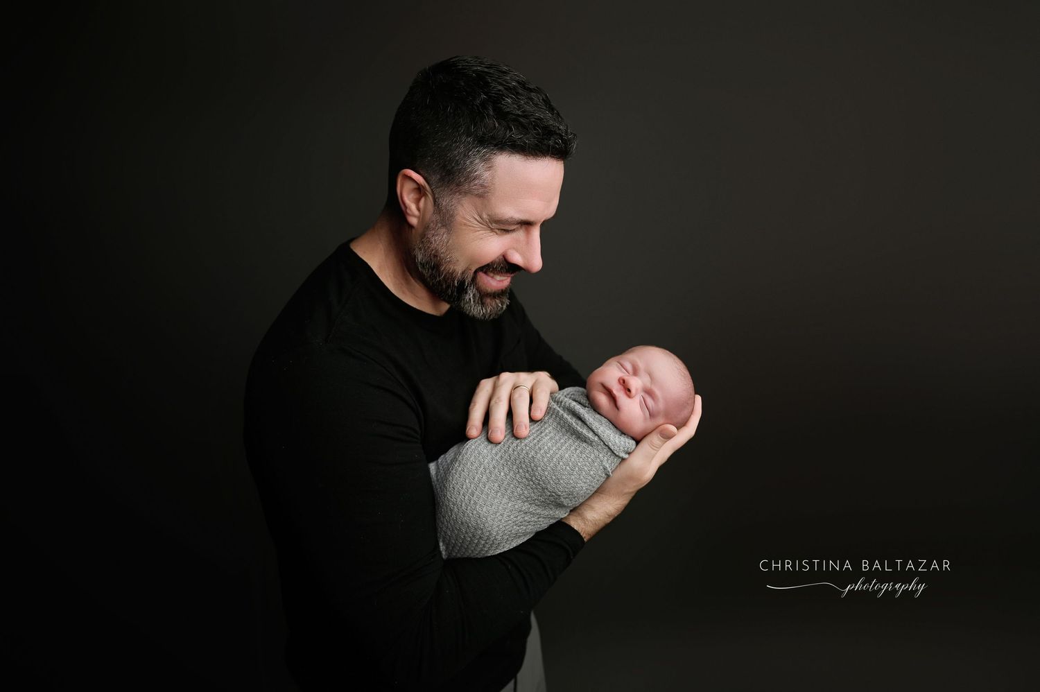 A dramatic newborn photo session shows a baby being gently cradled in artistic poses. Fresno Newborn Photography