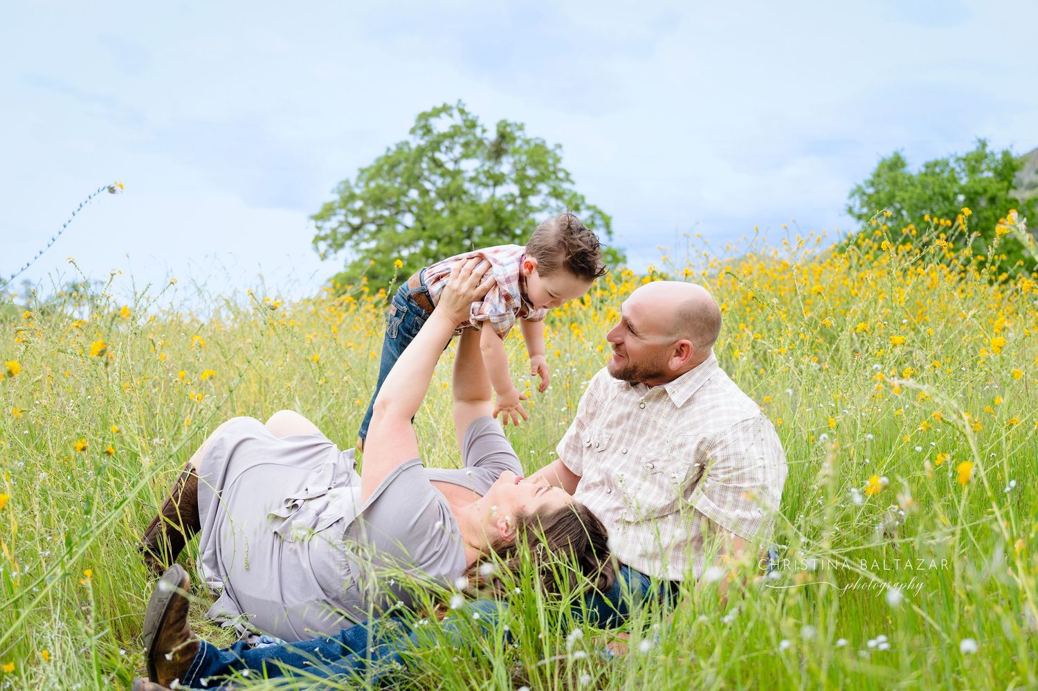 People enjoying a sunny day together while sitting in a wildflower meadow with tall yellow grass. Fresno Family Photography