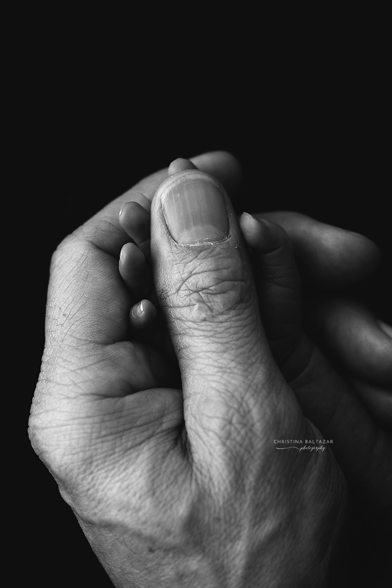 Artistic black and white macro shot of fingers intertwined against dark backdrop.