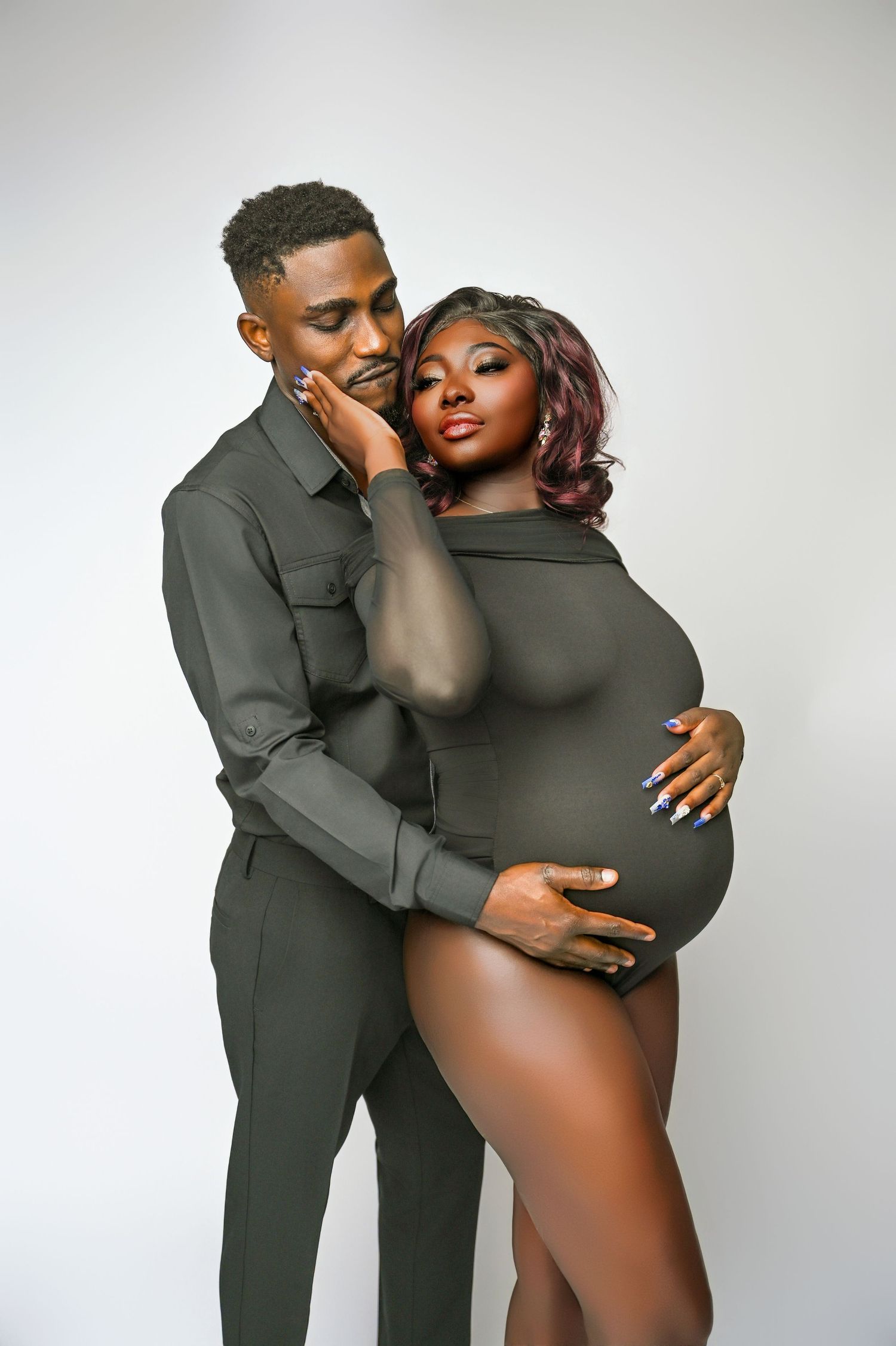 Intimate maternity portrait of couple in coordinating dark outfits.