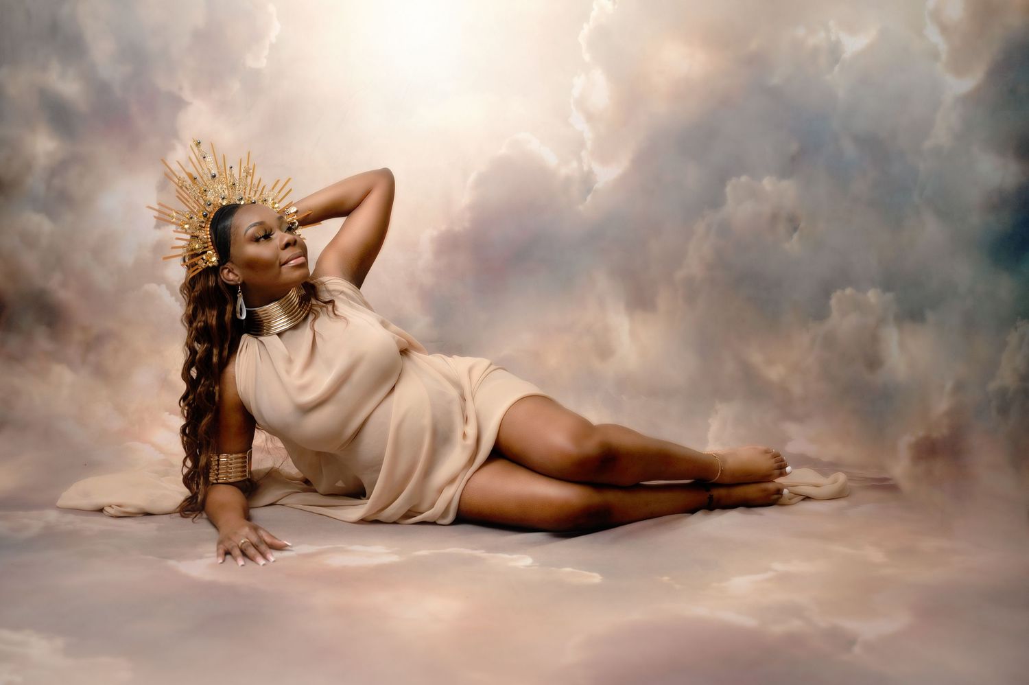 Ethereal portrait of a woman in white dress reclining against dramatic cloudy backdrop. Fresno Maternity Photographer