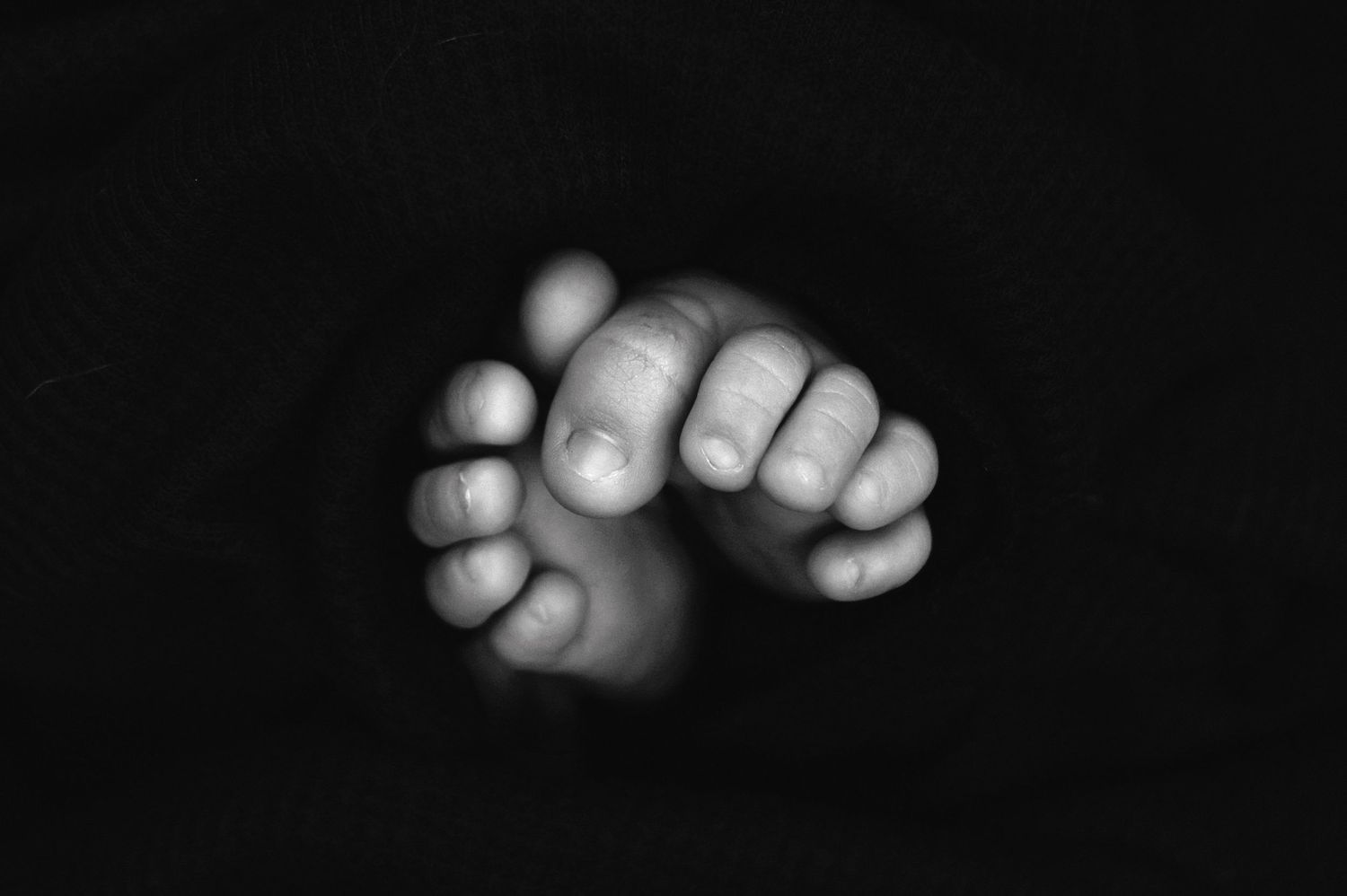 Black and white series of tiny baby toes and feet against dark background. Fresno Newborn Photographer