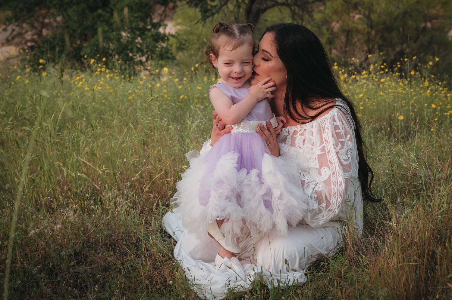 Tender moment captured between parent and child in field of wildflowers. Fresno Family Photography