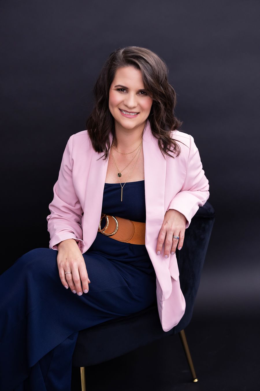 Professional portrait series featuring a pink blazer and navy dress against a dark background.