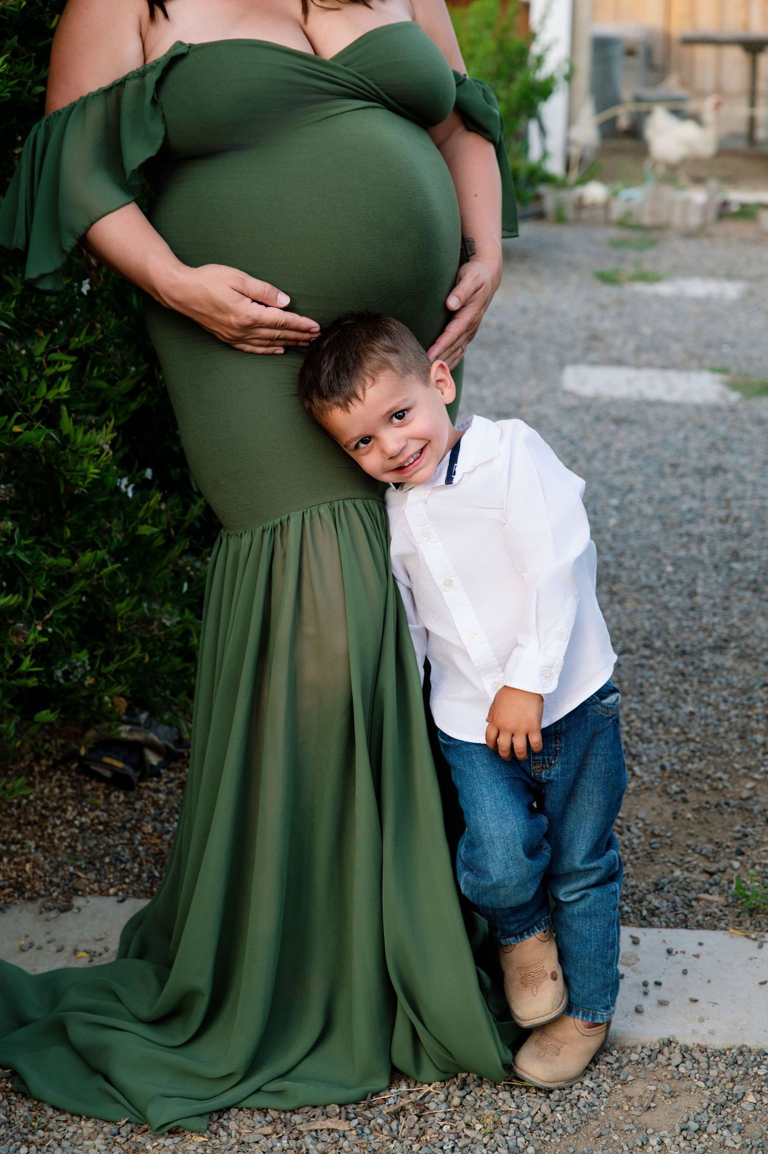 An intimate maternity moment captured in an olive green dress amidst a garden setting.