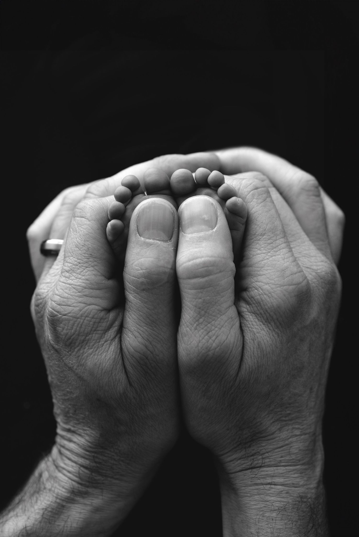 Black and white photograph showing a sequence of clenched fists with knuckles facing the camera against a dark background.