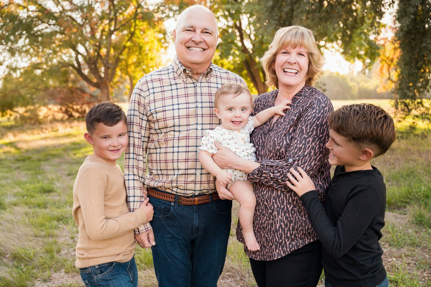Multi-generational family group shares warm embraces during outdoor fall photo session. Hanford Family Photographer