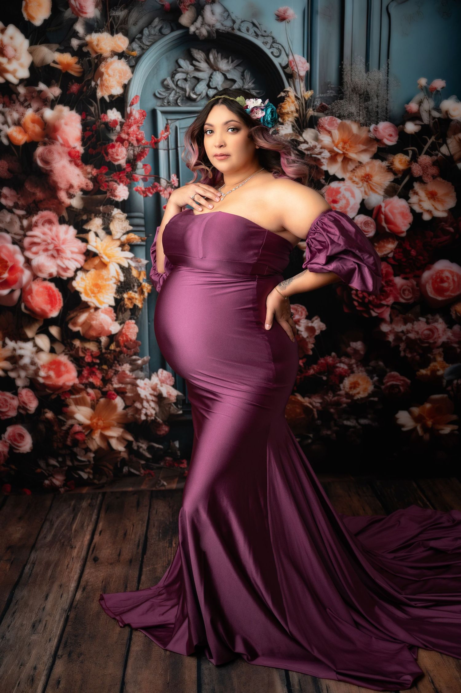 Maternity photo with purple gown and floral backdrop.