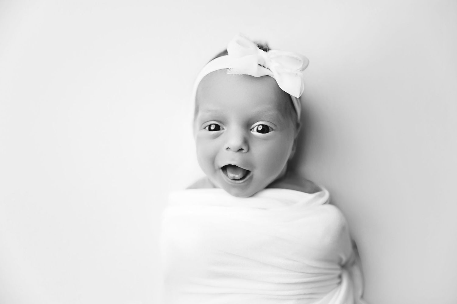 Black and white photo series showing close-up portraits of a baby in different expressions and poses.