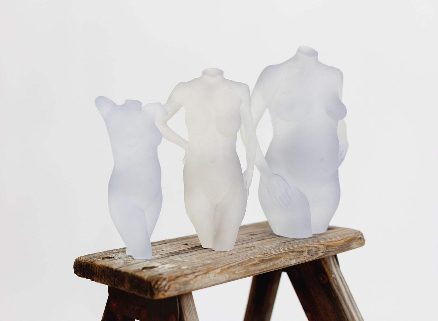 Three frosted transparent pregnancy sculptures displayed on a rustic wooden ladder against a white background in Central California