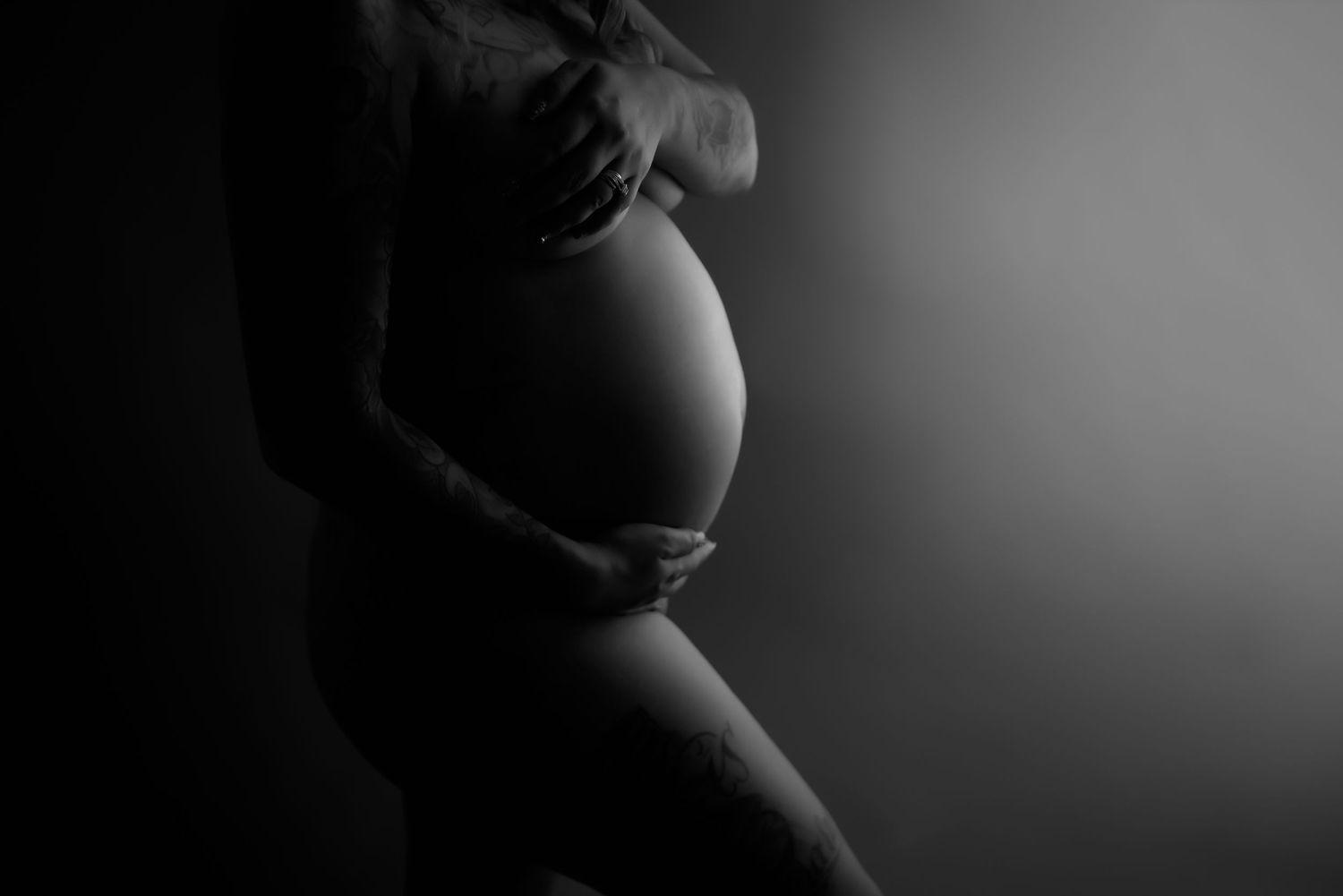 Black and white artistic silhouette of pregnant belly in dramatic lighting. Fresno Maternity Photographer
