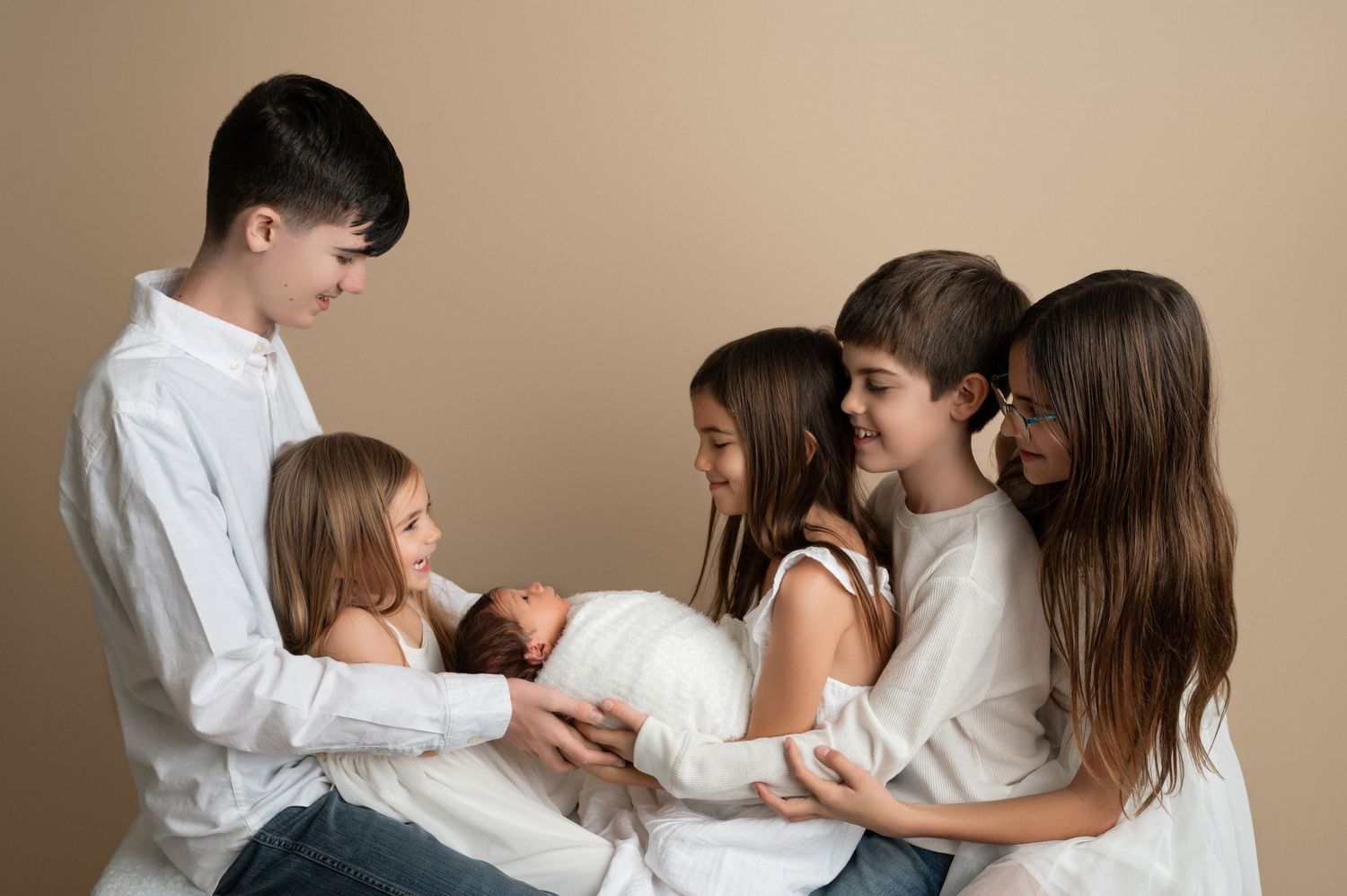 Siblings gathered closely together sharing a special moment with their baby sibling.