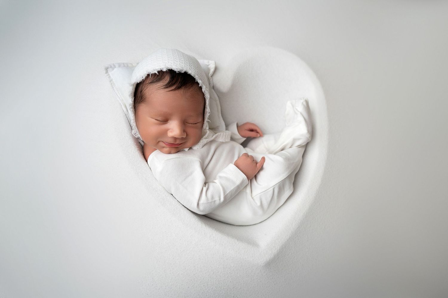 Simple white newborn photography series showing peaceful sleeping poses.