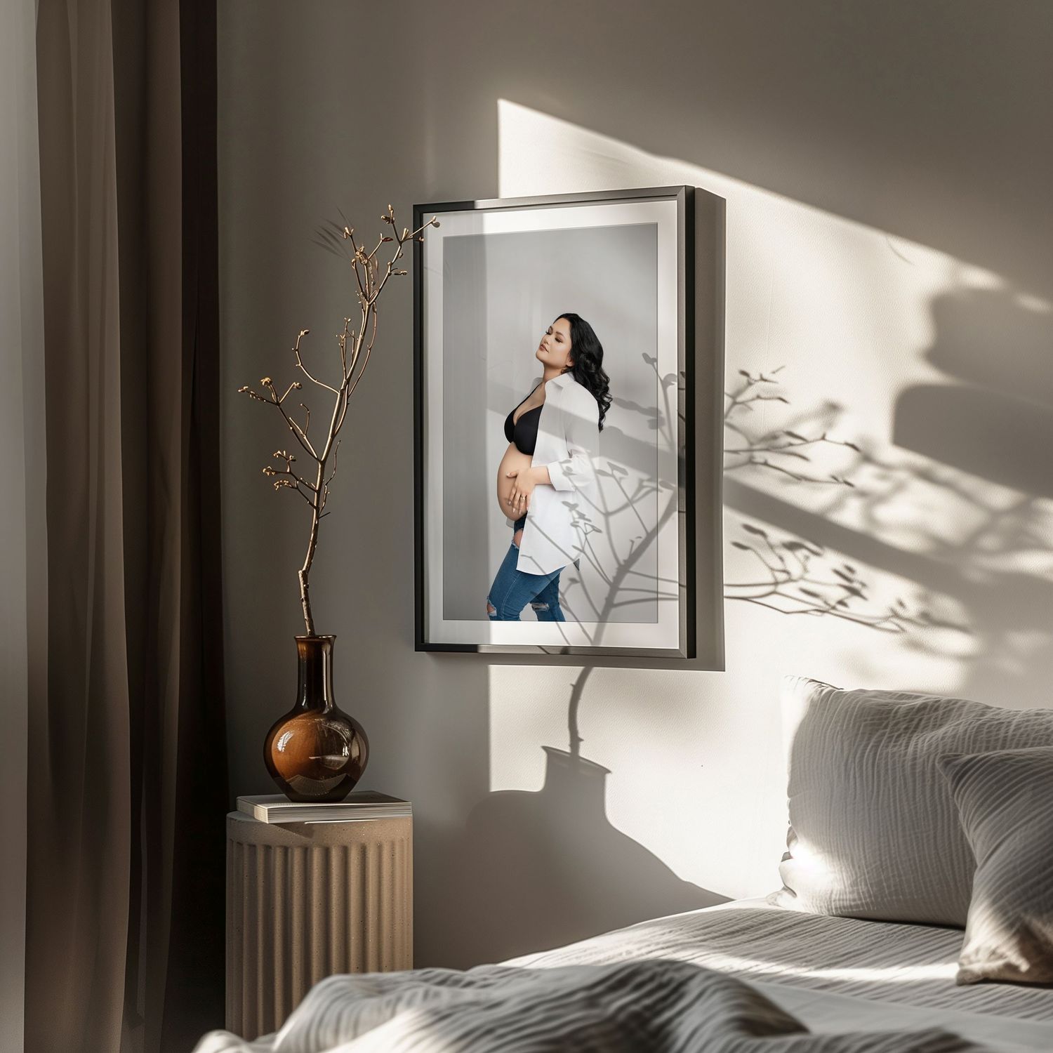 Minimalist bedroom interior with dramatic sunlight casting shadows through window onto gray walls and white bedding. Hanford Maternity Photo