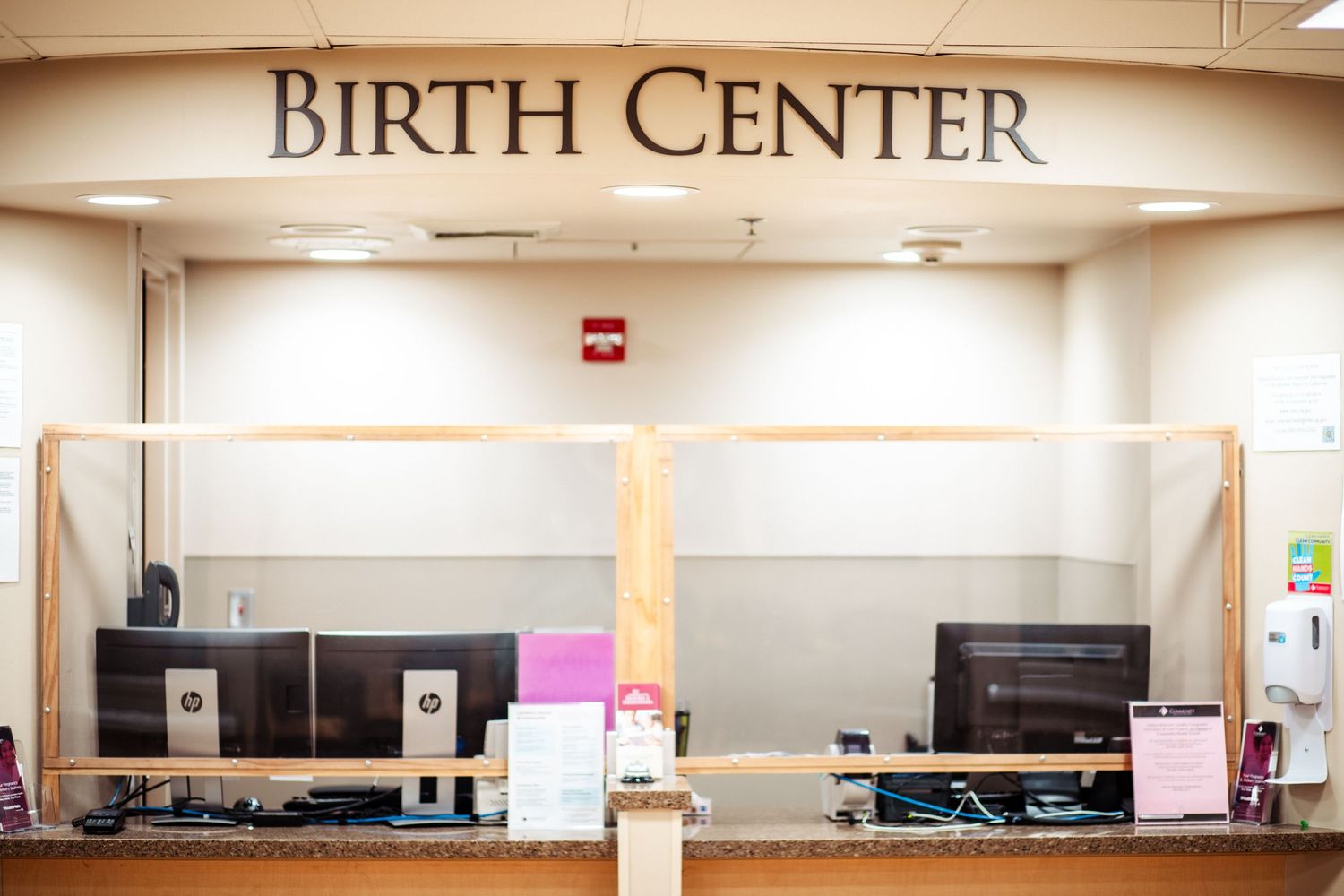 Reception desk area of a Birth Center with computers and sign above.