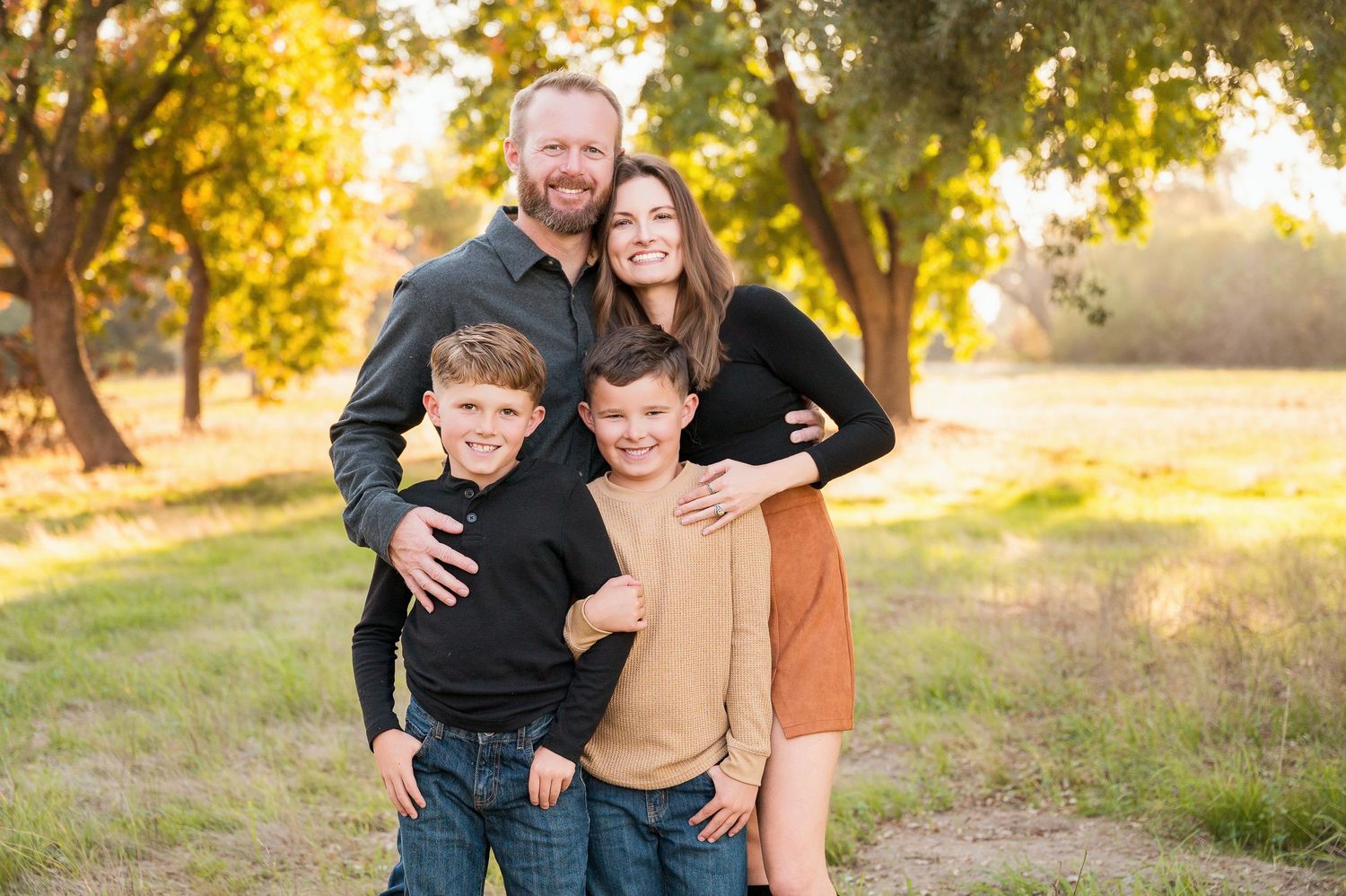 Family portrait session in golden sunlight with fall trees in background. Hanford Family Photographer