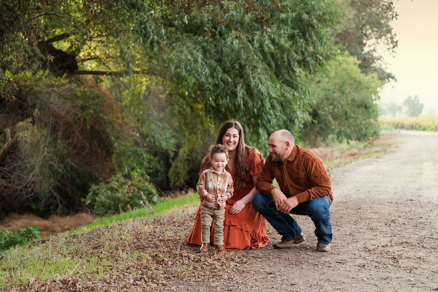 Casual family photo session with natural interactions on a dirt path surrounded by greenery. Hanford Family Photographer