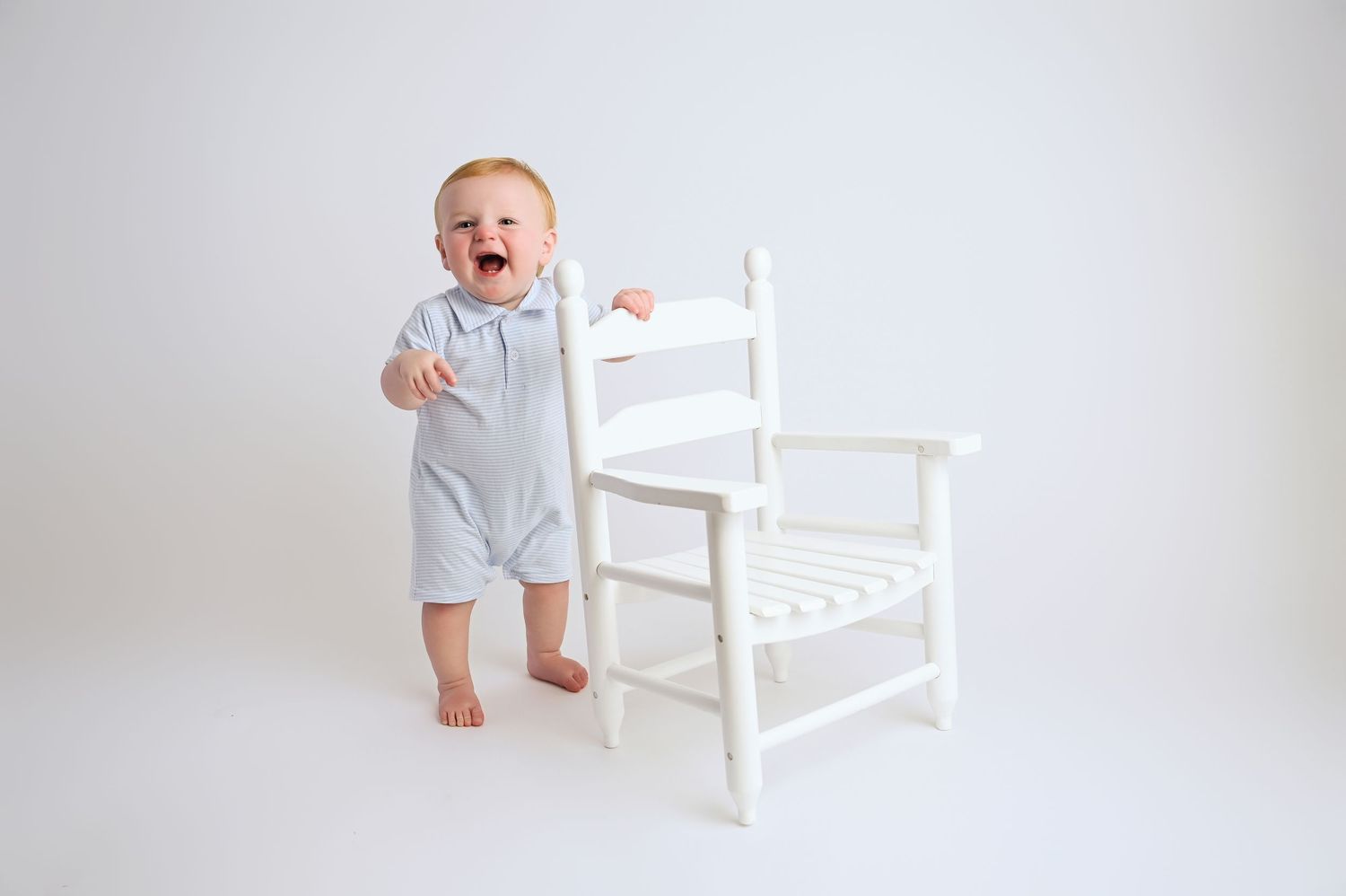 Sequence of baby expressions while seated in white wooden chair against white background. Hanford Cake Smash Photographer