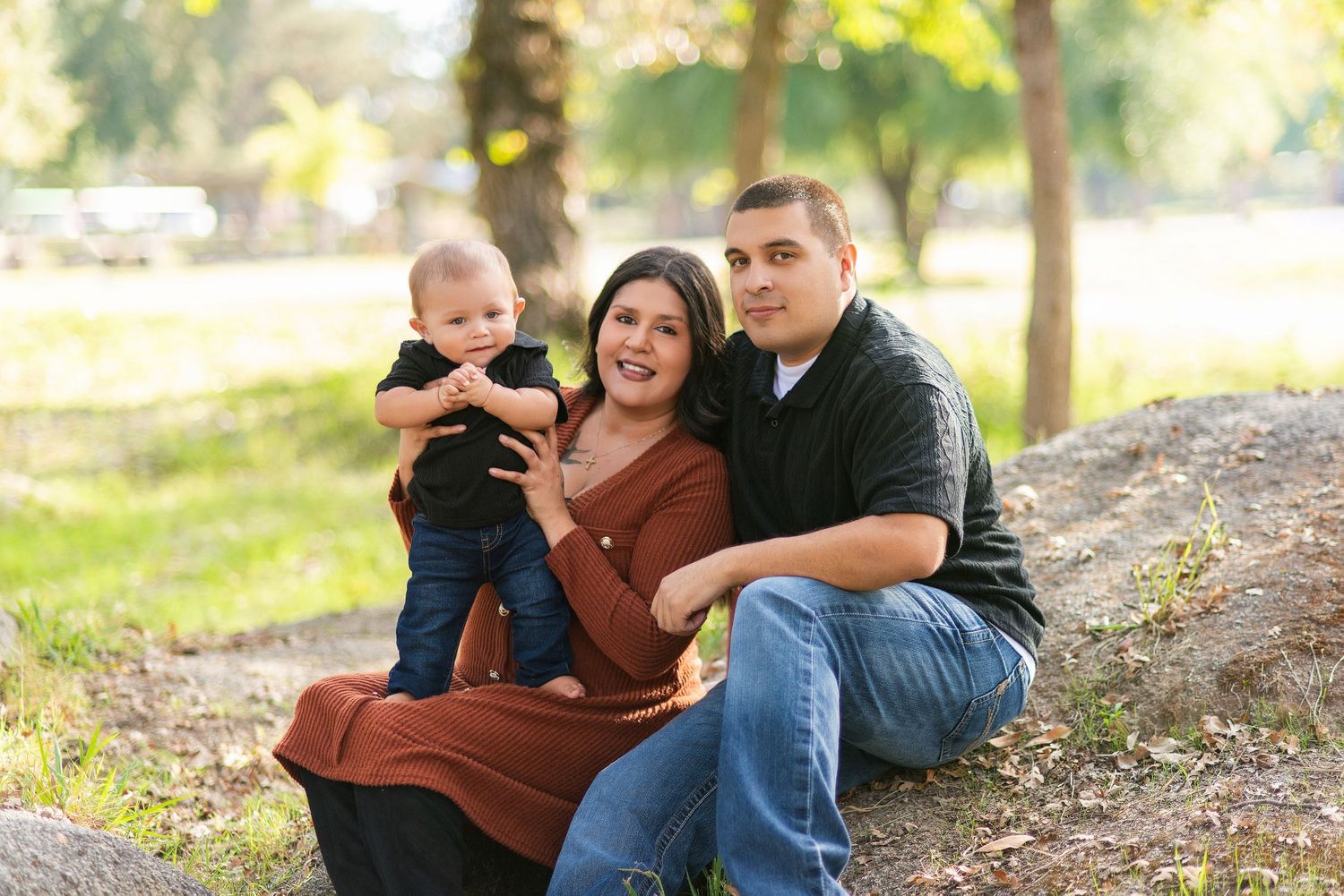 Casual family portrait session captured outdoors in autumn sunlit park setting.
